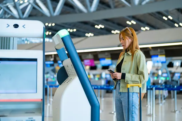 Viajera junto a un quiosco de autofacturación en la terminal