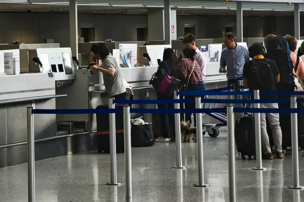 Pasajeros con maletas en la cola de los mostradores de facturación