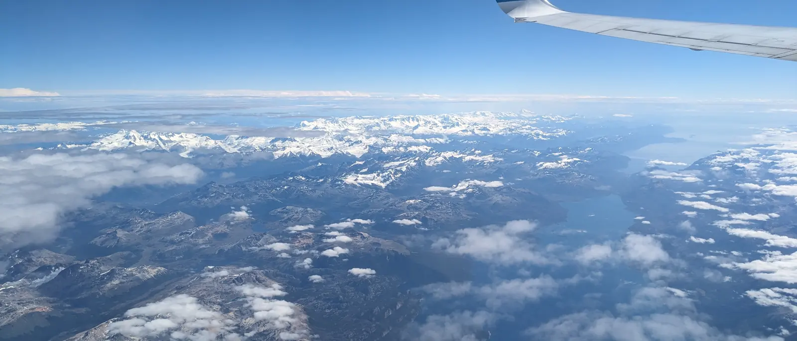 Vista aérea de montañas y nubes desde la ventanilla de un avión